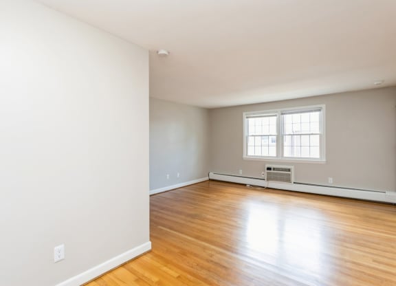 the living room of an empty house with white walls and wooden floors