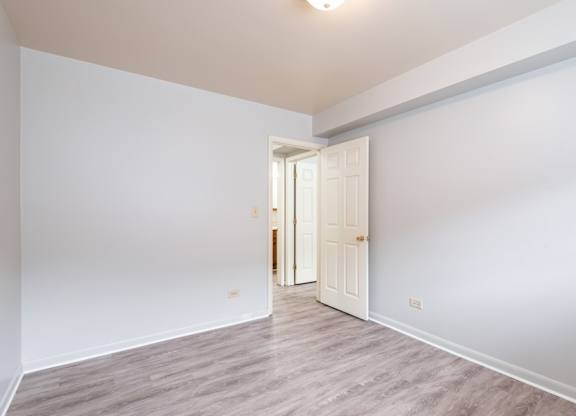 A room with a white door and grey flooring.