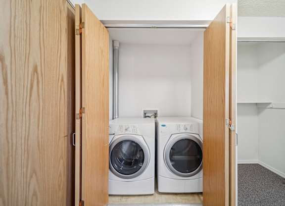 Two washing machines are in a small laundry room.