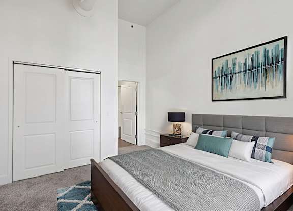 A bedroom with a bed, nightstand, and a painting on the wall.