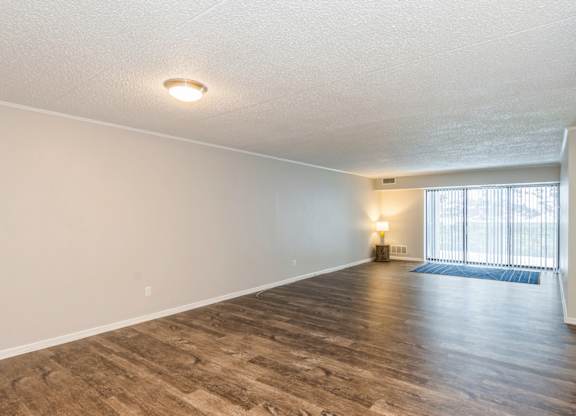 A spacious living room with wooden flooring and a window