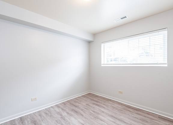 A room with a window and wooden flooring.