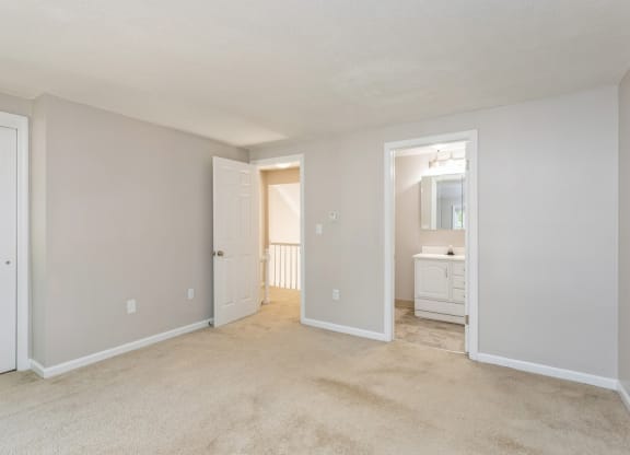 empty room with two doors with one on looking at the hallway and one into the bathroom