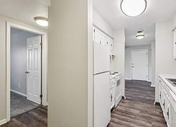 A kitchen with white appliances and cabinets.