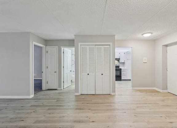 A room with white walls and wooden flooring with a white door in the center.