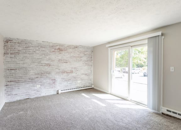 an empty living room with a brick wall and glass door at Stonebridge, Ellington, Connecticut
