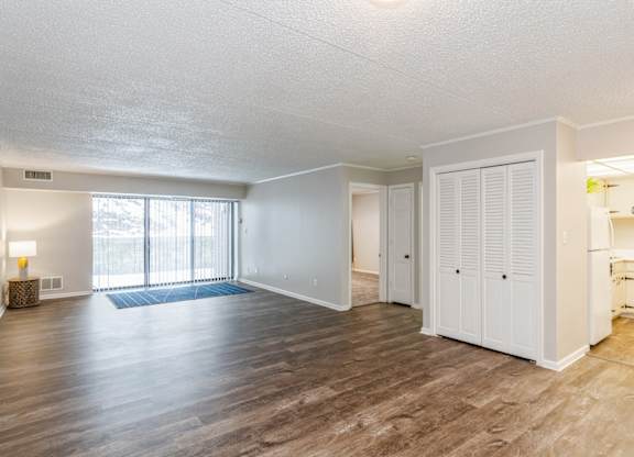 A spacious living room with wooden flooring, a window, and white doors