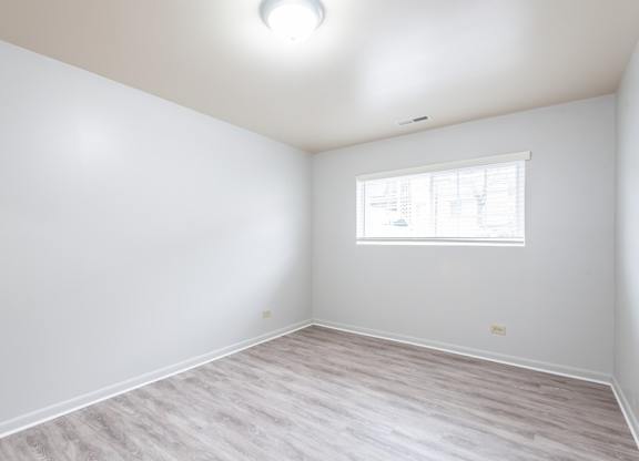 A room with a window and a wooden floor.