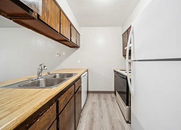 A kitchen with a wooden counter top and stainless steel appliances.