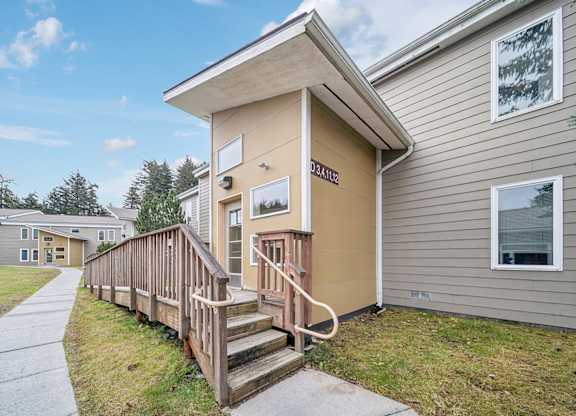 A small house with a porch and a brown railing.