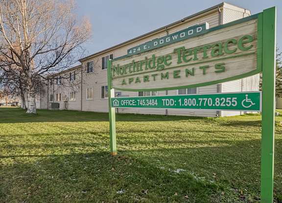 A green sign for Nookridge Terrace Apartments sits in front of a building.