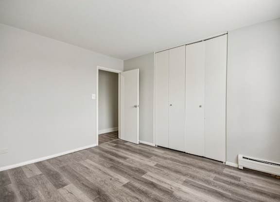 A room with a grey floor and white walls with a door and a wardrobe.