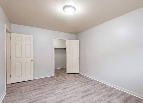 A room with a white ceiling and a wooden floor with two white doors.