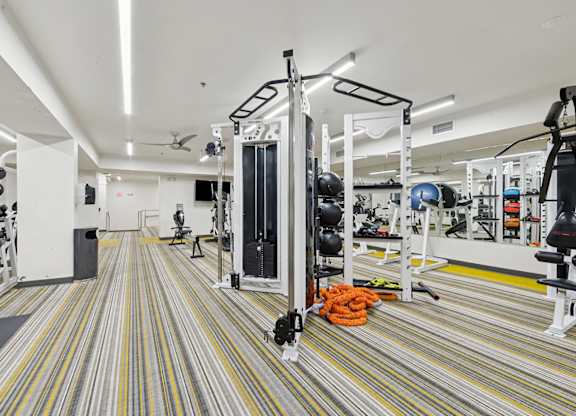 A gym with a striped carpet and a variety of equipment.