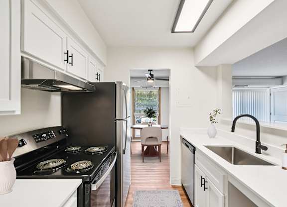 A modern kitchen with a black stove top oven and white cabinets.