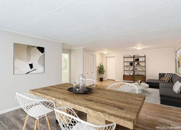 A living and dining room with a sectional sofa, wooden table, and white chairs.
