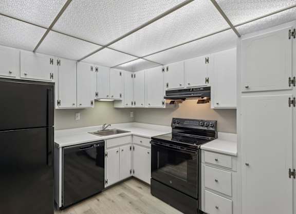 A kitchen with white cabinets and black appliances.