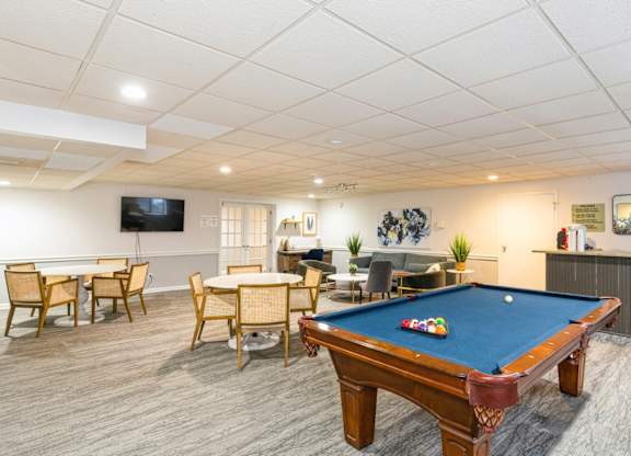 A pool table is in the middle of a room with a TV and a dining table.