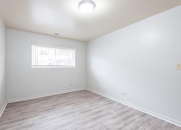 A room with a window and wooden flooring.