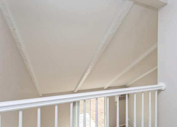the attic of a home with a white railing and a window