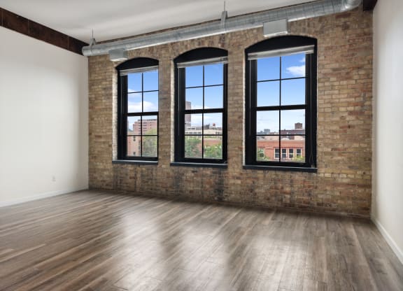 an empty room with a brick wall and three windowsat Gaar Scott Historic Lofts, Minnesota, 55401