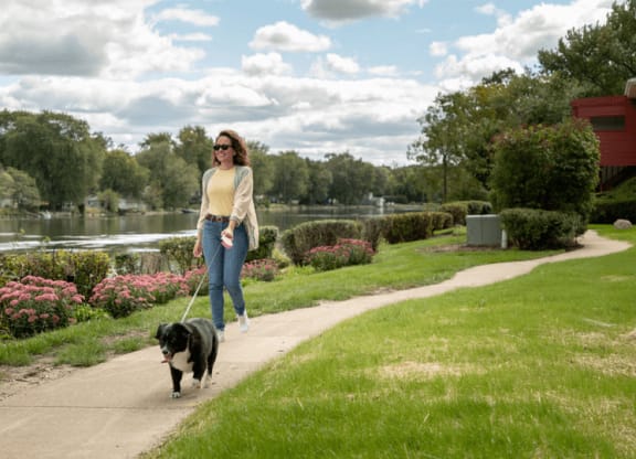 a woman walking her dog in a park at The View Apartments St Charles, Illinois