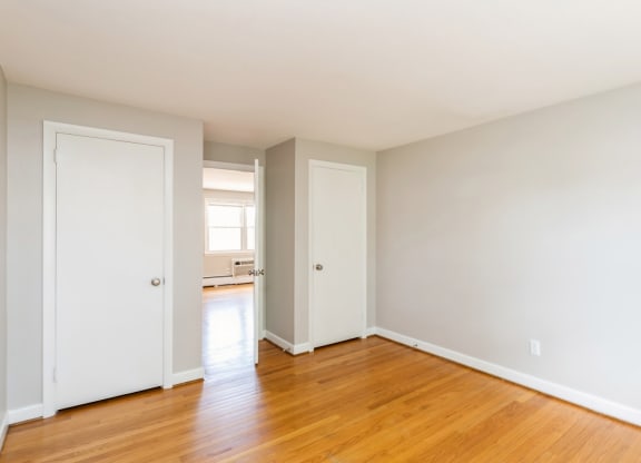 an empty bedroom with wood floors and white doors
