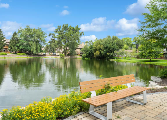 a bench overlooking a lake with houses and trees in the background at The Hinsdale, Illinois, 60521