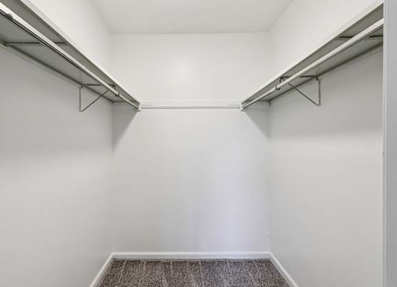 A white hallway with a carpeted floor and two metal rails on the wall.