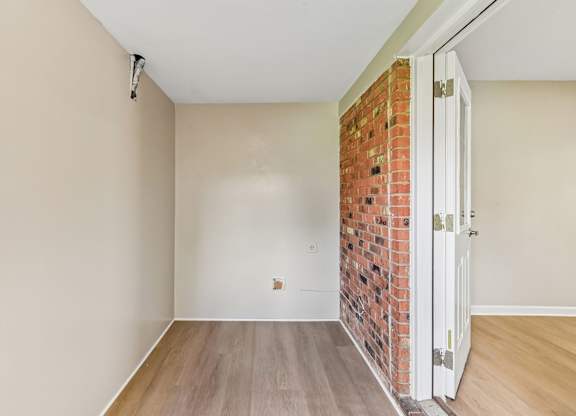 A room with a brick wall and wooden flooring.