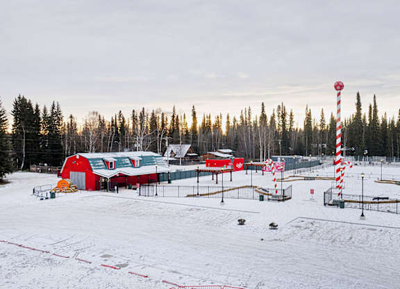 A snowy landscape with a red and white striped pole in the foreground.