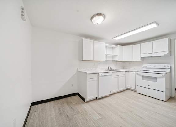 A white kitchen with a wood floor and white cabinets.