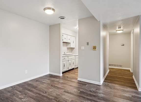 A kitchen with white cabinets and a wooden floor.