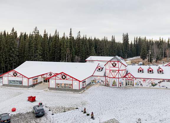 A large red and white building with a red roof and white trim is surrounded by snow.