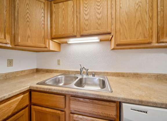 A kitchen with wooden cabinets and a stainless steel sink.