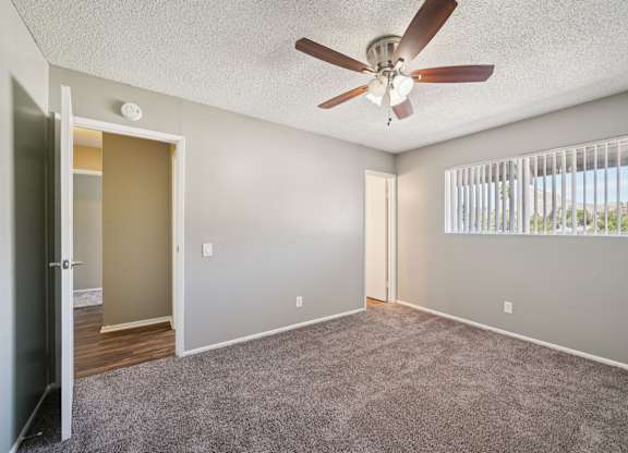 A room with a ceiling fan and a window with blinds.