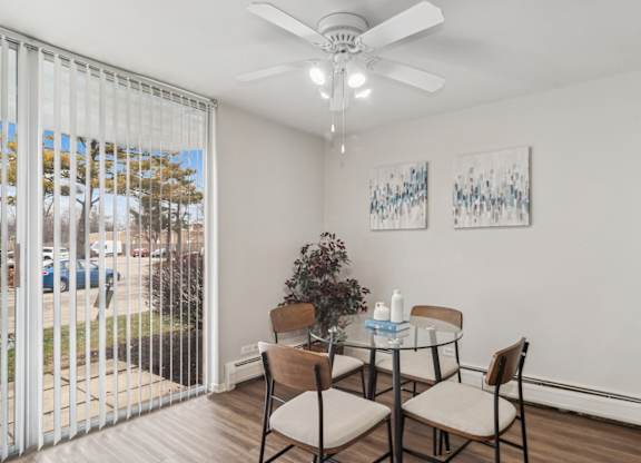 a dining room with a glass table and chairs and a ceiling fan