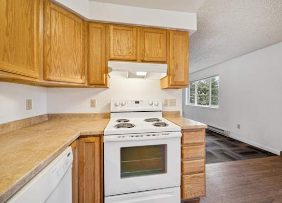A kitchen with wooden cabinets and a white stove top oven.