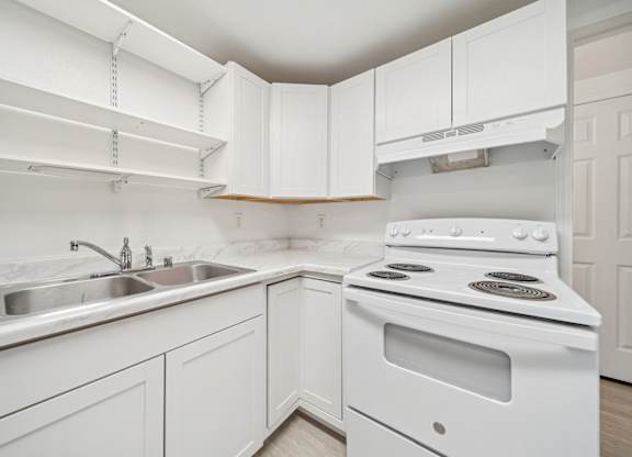 A white kitchen with a stove and sink.