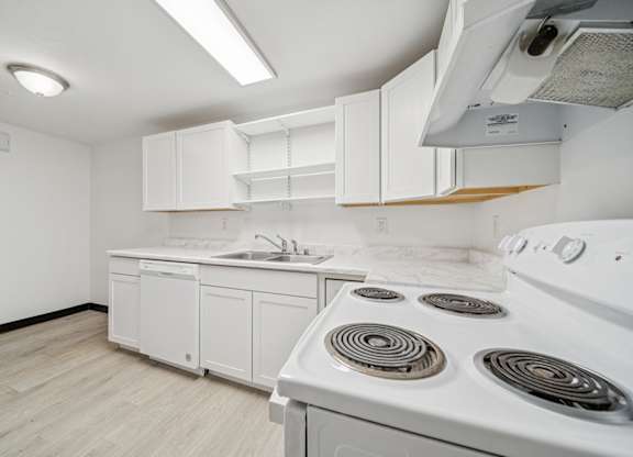 A white kitchen with a stove and sink.
