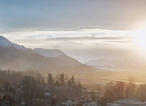 A sunrise over a mountain range with a town in the foreground.