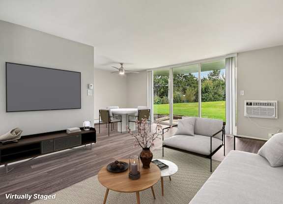A living room with a grey couch, a wooden coffee table, and a flat screen TV mounted on the wall.