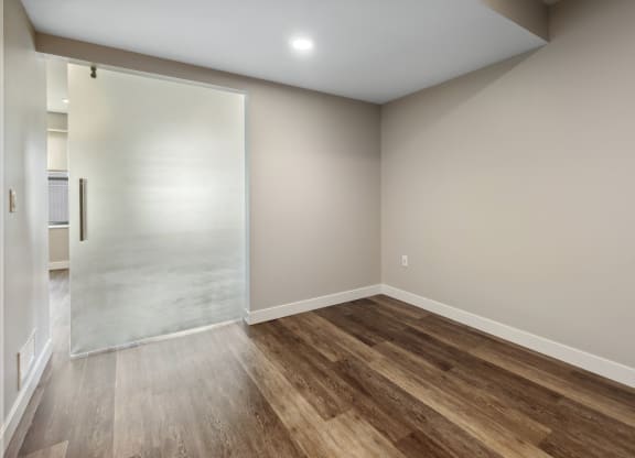 an empty room with wood flooring and a sliding glass door at The Rowe, Grand Rapids, 49503