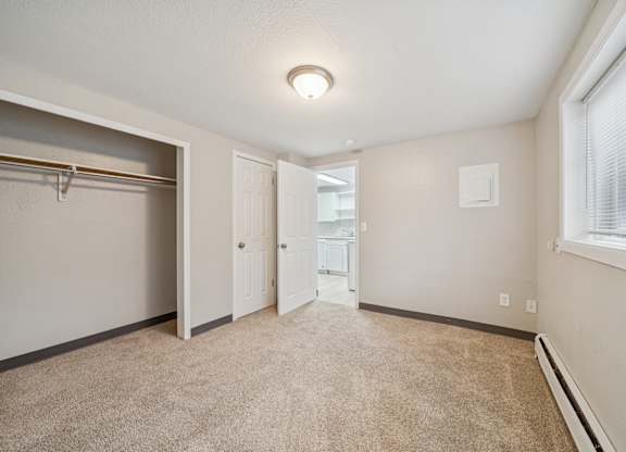 A room with a carpeted floor and a window with blinds.