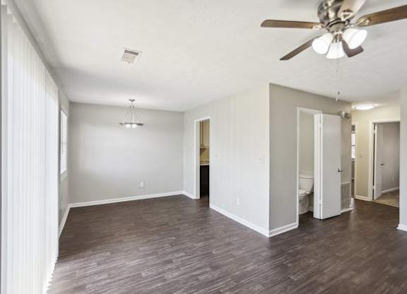 A room with a ceiling fan and wooden flooring.