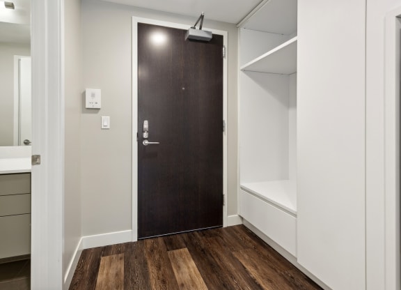 a wardrobe with a wooden door in a room with white walls and wood flooring at The Rowe, Grand Rapids, 49503