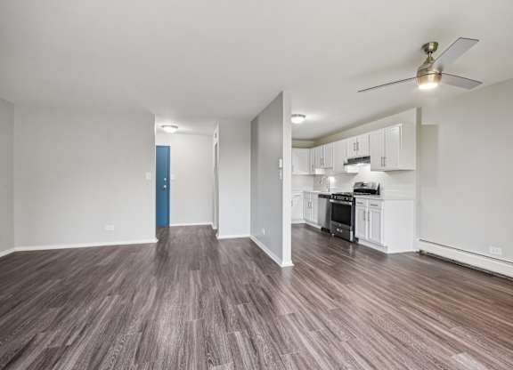 A room with a kitchen area and a wood floor.