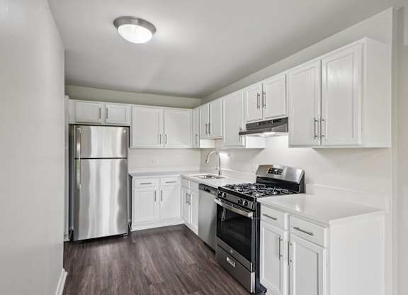 A kitchen with white cabinets and a stainless steel refrigerator.