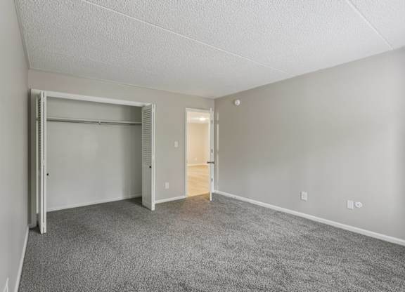 A bedroom with a grey carpet and white walls.