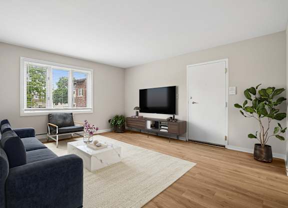 A living room with a blue couch, a white coffee table, and a flat screen TV.